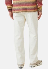 Witte corduroy broek met een relaxed fit, gecombineerd met beige sneakers. De corduroy textuur is zichtbaar, met verticale ribbels.