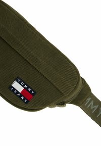 Sac banane en velours côtelé vert olive Tommy Jeans avec rabat avant et patch logo brodé rouge, blanc et marine.
