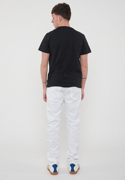 T-shirt nera a maniche corte abbinata a pantaloni bianchi a gamba dritta. Presenta un classico colletto tondo ed è realizzata in morbido tessuto di cotone.