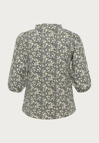 Kwiatowa bluzka z rękawami trzyczwartowymi, z czarnym tłem i białym nadrukiem kwiatowym, zaokrąglonym dołem i teksturowanym dekoltem ozdobionym falbaną.