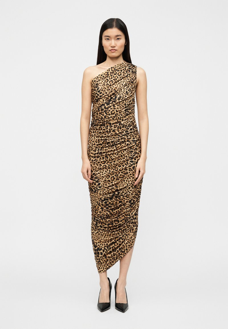 Φόρεμα με σχέδιο λεοπάρ, ένα ώμο, με υφή draped, ασύμμετρο τελείωμα και μήκος μέχρι τον αστράγαλο. Το μοντέλο το συνδύασε με μαύρα ψηλοτάκουνα.