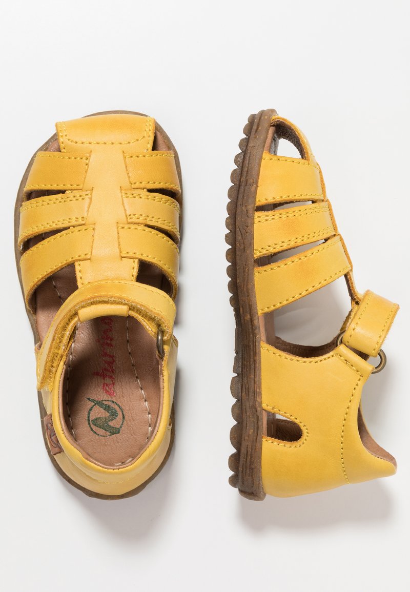 Žluté kožené sandály s otevřeným designem, které mají několik řemínků a suchý zip na kotníku. Texturovaná gumová podrážka s gripem.