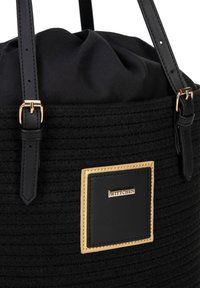 Borsa a secchiello nera in tessuto intrecciato con finiture in pelle nera, dotata di hardware in tono oro e una placca quadrata con logo. Spallacci in pelle regolabili.