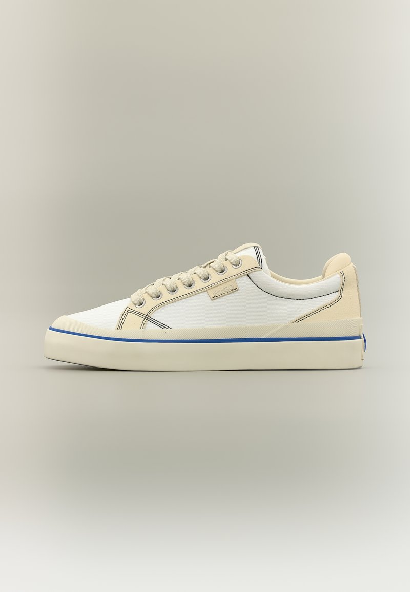 Baskets basses beige et blanches avec lacets à l'avant, bande bleue sur la semelle et étiquette discrète de la marque sur le côté.