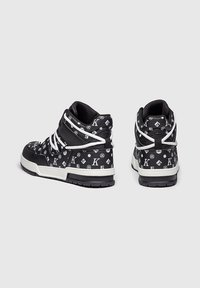 Černé vysoké tenisky s bílým logem, bílými tkaničkami, texturovaným povrchem a kontrastní bílou podrážkou.