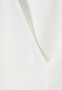 Blusa bianca con scollatura a V profonda, tessuto liscio con una leggera lucentezza e cuciture sottili lungo le cuciture. Design semplice ed elegante.