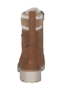 Bottine en daim marron avec un col en tricot texturé, fermeture éclair arrière et semelle en caoutchouc blanche. Design simple avec un détail de logo minimal.