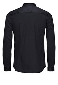 Chemise noire à manches longues boutonnée, vue de dos, avec col et poignets boutonnés.