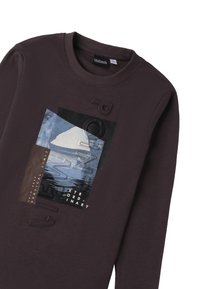 Ciemnobrązowy długi sweter z grafiką w technice mixed-media, zawierającą niebieskie i czarne tekstury oraz warstwowe elementy tekstowe.