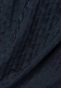 Dunkelblauer Stoff mit einem subtilen gewebten Leopardenmuster, der weiche Falten und Textur zeigt, die die Details des Gewebes betonen.