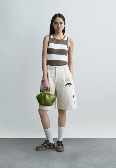 Débardeur côtelé à rayures marron et blanc, short beige brodé, sac à main vert, baskets olive et chaussettes blanches mi-mollet.