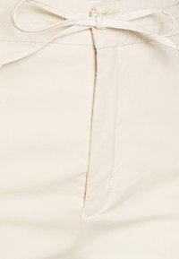 Beige Baumwollhosen mit einer gebundenen Kordel am Bund, einer Naht vorne und subtiler Textur, geeignet für legere Anlässe.