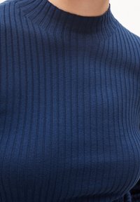 Pull côtelé bleu marine avec un col montant, présentant un motif texturé et une coupe ajustée. Tissu tricoté doux avec des rayures verticales.
