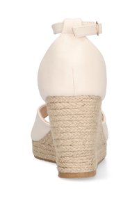 Zapato de tacón en cuña beige con parte superior lisa, correa en el tobillo con herrajes en tono dorado y tacón envuelto en yute. Diseño de parte trasera cerrada.