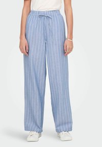 Hele sinised, laia lõikega püksid, millel on vertikaalsed valged triibud, elastne vöökoht ja reguleeritav pael. Valmistatud pehmest, hingavast kangast.