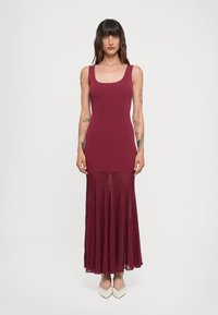 Abito borgogna con top aderente e gonna plissettata, realizzato in tessuto leggero. Presenta un scollo quadrato e una silhouette fluida.
