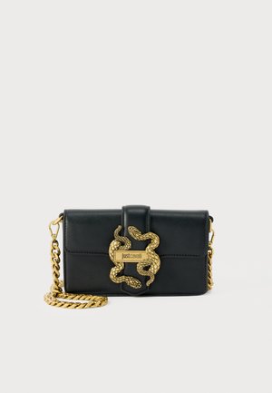 Black leather crossbody bag with gold chain strap and decorative gold snake buckle on front flap closure.