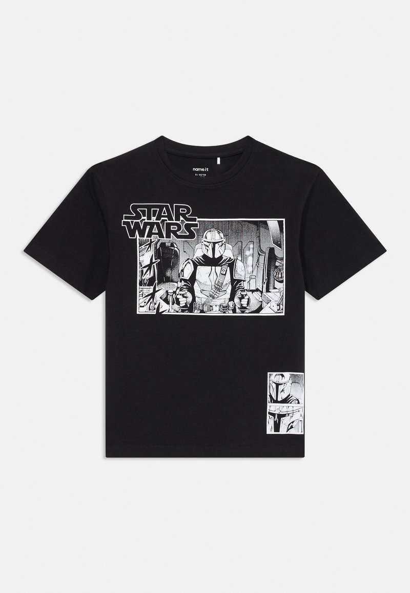 Svart T-skjorte med Star Wars-grafikk som viser en Mandalorian-karakter i rustning, som holder kontroller i cockpiten av et romskip.