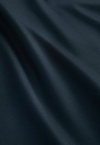 Tejido azul marino con una textura suave y ligeramente brillante, que muestra sutiles ondas y pliegues. El material parece suave y ligero.