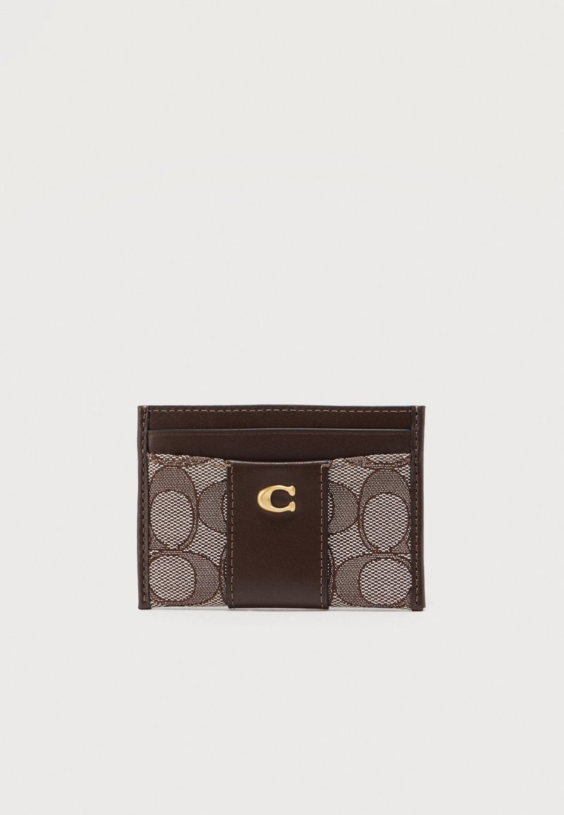 Καφέ δερμάτινο και υφασμάτινο θήκη καρτών με το χαρακτηριστικό μοτίβο "C" και χρυσό έμβλημα με το γράμμα "C" στο κέντρο, σχεδιασμένη για να κρατά κάρτες.