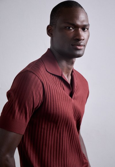 Polo maroon à côtes avec col, manches courtes et silhouette ajustée, fabriqué en tissu tricoté texturé.
