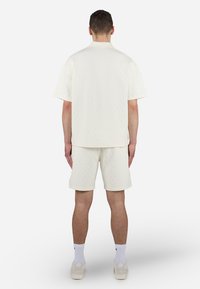 Set di maglietta e pantaloni corti in maglia strutturata color crema, caratterizzato da un motivo a rombi, vestibilità rilassata, maniche brevi e vita scesa.