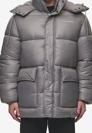 Personne portant une doudoune grise avec de grandes poches avant, une capuche avec des cordons de serrage et le nom de la marque Pegador sur la poitrine.