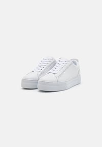 Sneakers bianchi con un upper in pelle liscia, lacci piatti e una suola piatta testurizzata. Presentano un dettaglio con cerniera laterale e un design minimalista.