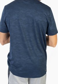 Námořnické modré tričko s krátkým rukávem, které je zdobeno texturovaným maskáčovým vzorem, vyrobené z prodyšného materiálu s běžným střihem a zakřiveným lemem.