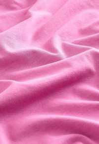 Tessuto rosa tenue con texture liscia, caratterizzato da pieghe e arricciature delicate che evidenziano la sua leggerezza ed elasticità.
