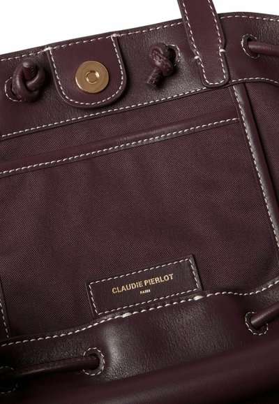 Borsa bordeaux con tessuto testurizzato e dettagli in pelle liscia. Elementi in metallo dorato e cuciture bianche evidenziano i dettagli di design.