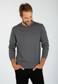 Maglione grigio a maniche lunghe realizzato in un morbido materiale a maglia, con scollatura rotonda e polsini e orlo a costine. Design semplice senza motivi.