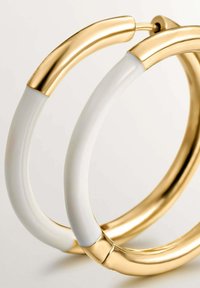 Pendientes de aro en oro y blanco con un acabado suave y brillante, que presentan formas curvadas y juntas sin costuras, realzando su diseño minimalista.