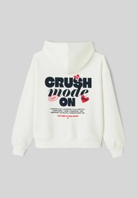 Sweat à capuche blanc avec un grand texte noir « CRUSH mode ON », agrémenté d'accents en forme de cœur rouge et d'un texte détaillé en noir et rouge en dessous.