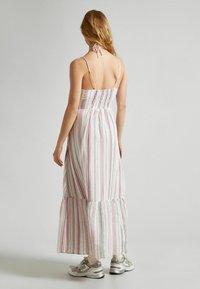 Ilga suknelė iš lengvos medžiagos su vertikaliomis rožinėmis ir žalios juostomis, suraukta nugarėlė, plonytės petnešėlės ir sluoksniuota apačia. Suderinta su pilkais sportbačiais.