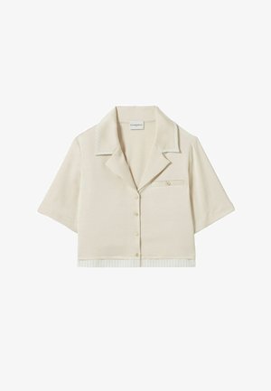 Camisa corta de manga corta beige recortada con cuello con muesca, pequeño bolsillo en el pecho con botón y sutil ribete a rayas en el cuello y el dobladillo.