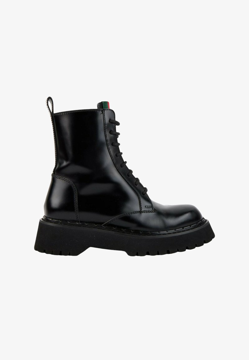 Botte en cuir noir brillant à lacets avec semelle épaisse à crampons et languette à l'arrière, montrée de profil sur fond blanc.