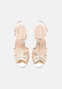 Χρυσά μεταλλικά σανδάλια με ανοιχτό δάχτυλο, με σχέδιο με λουράκια και ρυθμιζόμενο λουράκι στον αστράγαλο. Ομαλή υφή με κομψό, σύγχρονο στυλ.