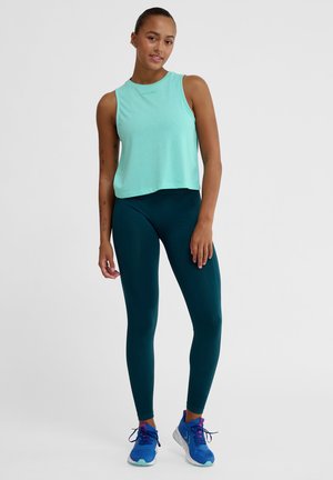 Mint green sleeveless crop top paired with dark teal leggings and blue athletic shoes, featuring a smooth fabric and fitted design.