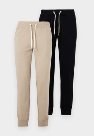 Twee paar sweatpants: één beige en één zwart, met elastische boorden en een trekkoord in de taille met zilveren hardwareaccenten.