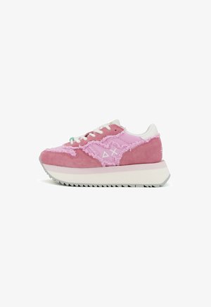 Zapatillas con un upper de ante y tela rosa, con detalles deshilachados, cordones blancos y una suela gruesa blanca y gris.