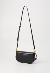 Borsa a spalla in pelle nera con forma curva, fronte piatto, accessori in oro e una lunga tracolla regolabile. Texture liscia con cuciture minime.