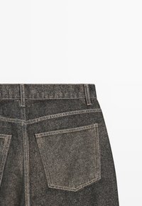 L'arrière d'un jean en denim gris foncé montrant la taille, les passants de ceinture, la couture du dos et une seule poche arrière avec des coutures visibles.