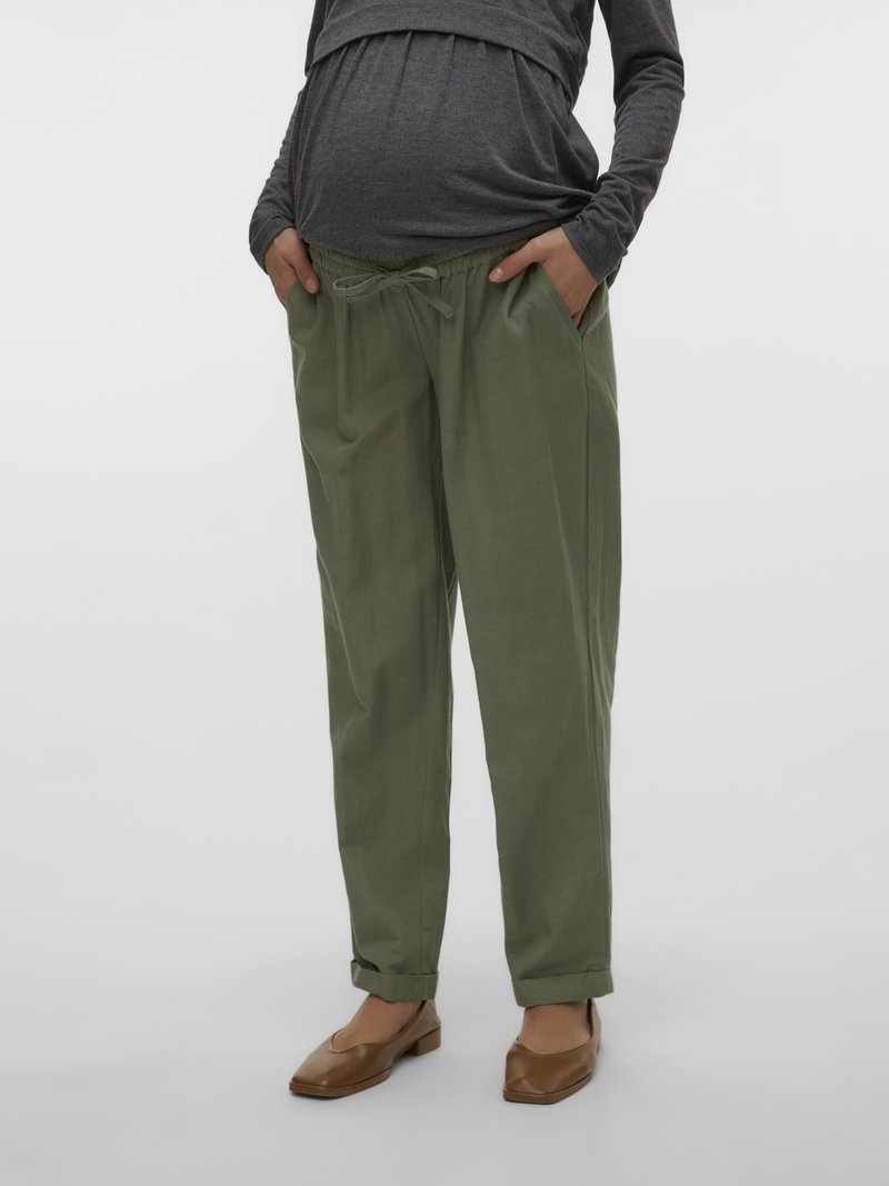 Rohelised kergekaalulised raseduspüksid küljetaskutega, elastse nööriga vöökohas ja rullitud äärega, mida sobitatud halli pika varrukaga särgi ja pruunide madalate kingadega.