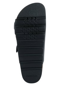 Svart gummisula med horisontella spår och perforeringar, med rundad baksida och upphöjd logotyp. Slät yta, ergonomisk design.