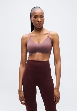 Draadloze bh in gedempt mauve, met verstelbare bandjes en lichte vulling. Gecombineerd met high-waisted bordeaux legging met zijzakken.