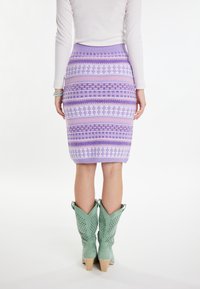 Fustă creion tricotată în nuanțe de lavandă și roz cu modele geometrice. Purtați cu cizme cowboy verzi, cu un design perforat și toc gros.