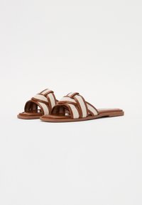 Brune slide sandaler med en vævet stofoverdel, der har stribede mønstre. Flad sål med en glat finish. Åben tå-design.