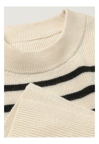 Krémový svetr s černými pruhy. Má ribbovanou výstřih a texturované pletení. Obsahuje silný pletený vzor na rukávech a těle.