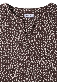 Blouse marron à motif abstrait à pois blancs, encolure fendue, et étiquette marquée "Cecil" au col.